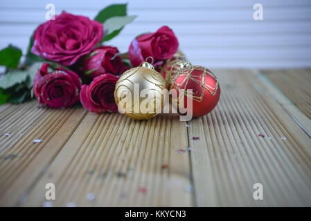 Natale romantico immagine di fotografia con oro glitter tree baubles di decorazione e fresche rose rosse sul naturale legno rustico sfondo Foto Stock