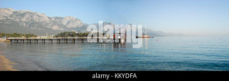 Kemer Antalia bella vista sul mare. Spiaggia Kemer Antalia con sabbia e montagne, il mare con la nave. Bellissimo porto vicino alla spiaggia di sabbia. Foto Stock