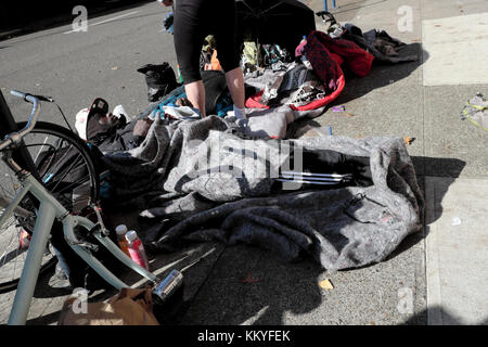 Un senzatetto che dorme sul marciapiede in mezzo le biciclette e i loro beni in Portland Oregon 2017 USA KATHY DEWITT Foto Stock