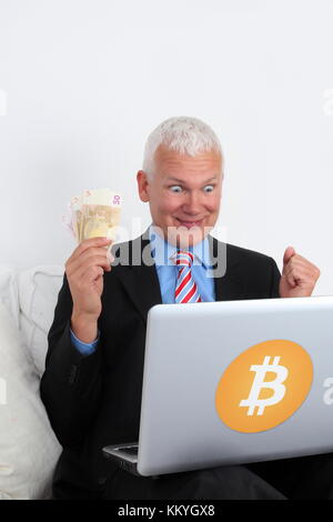 Un banchiere bitcoin investor felice con il computer portatile e denaro Foto Stock