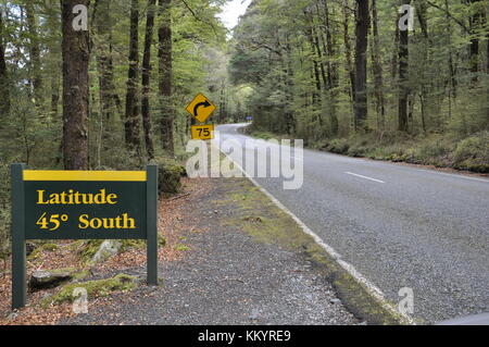 Latitude 45 gradi a sud cartello stradale lungo il Milford Sound autostrada, Parco Nazionale di Fiordland, Nuova Zelanda Foto Stock