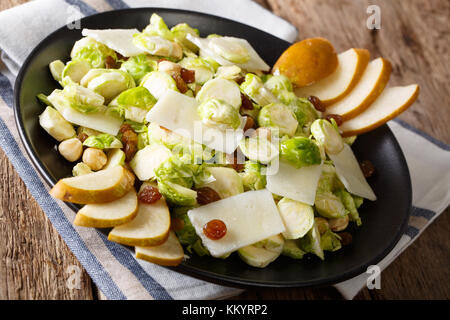 Insalata di cavoli di Bruxelles con i dadi, formaggio, uva e pere fresche closeup su una piastra orizzontale. Foto Stock