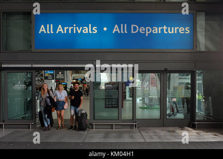 Le persone che trasportano bagagli a piedi attraverso l'ingresso all'Aeroporto Internazionale di Città del Capo (CPT) sotto un cartello che diceva ' tutti gli arrivi tutte le partenze' Foto Stock