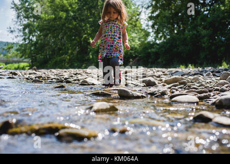 Una bambina sorge in un flusso su un soleggiato, giorno d'estate. Foto Stock