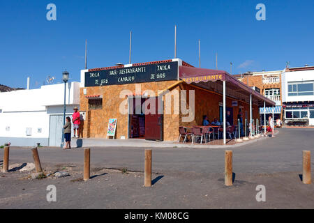Ristorante fronte spiaggia ad Ajuy sull'Isola delle Canarie di Fuerteventura. Le colonnine fermano le auto che si stazionano dalla strada sulla sabbia nera. Foto Stock