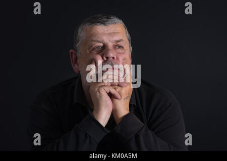 Nizza chiave di basso ritratto del barbuto senior caucasica uomo meditando nel buio Foto Stock