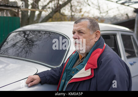 Bel ritratto di senior uomo in piedi vicino alla sua vecchia auto Foto Stock
