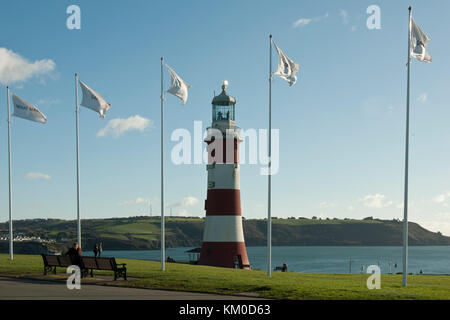 Contro un cielo blu e il mare sorge l'iconico smeatons tower lighthouse, dipinta in rosso/ strisce bianche; il Plymouth Hoe Foto Stock