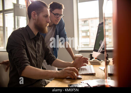 Due giovani uomini al lavoro con il computer Foto Stock