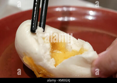 Il movimento di persone mangiare cotto a vapore tuorlo d'uovo bun ristorante interno Foto Stock