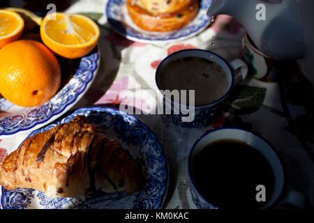 Sul tavolo c'è un caffè, croissant, arancio, tè. Foto Stock