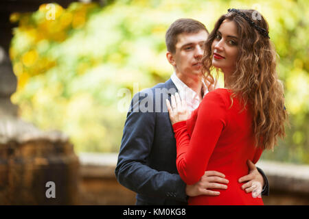 Ragazzo in costume classico abbraccia la ragazza in abito rosso Foto Stock