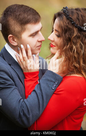 Ragazzo in costume classico abbraccia la ragazza in abito rosso Foto Stock