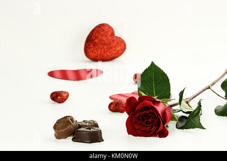 Bella gambo lungo una rosa rossa con cioccolato candy. profondità di campo. Foto Stock