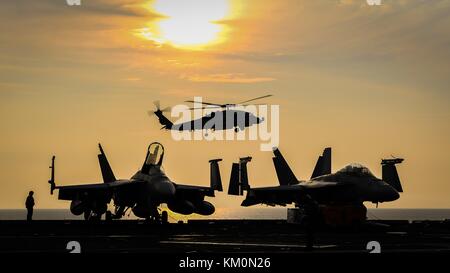 Un U.S. NAVY MH-60s seahawk elicottero atterra sul ponte di volo della marina degli Stati Uniti nimitz-class portaerei USS Theodore Roosevelt al tramonto novembre 24, 2017 nell'oceano indiano. (Foto di spencer roberts via planetpix) Foto Stock