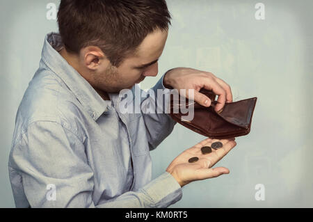 Monete e un portafoglio vuoto. il povero uomo tira fuori le ultime monete dalla sua borsa Foto Stock