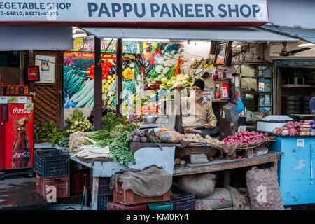 Maschio locale stallholder Sikh seduto a gambe incrociate in un negozio di vegetali, Amritsar e una città nel nord-occidentale dell'India nella regione di Majha del Punjab Foto Stock