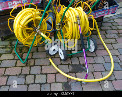 Due market garden avvolgitubo con giallo attorcigliare il tubo flessibile resistente su bobine portatile ed avente ugelli di spruzzo distribuzione conveniente in un garden center Foto Stock