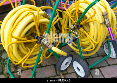 Due market garden avvolgitubo con giallo attorcigliare il tubo flessibile resistente su bobine portatile ed avente ugelli di spruzzo distribuzione conveniente in un garden center Foto Stock