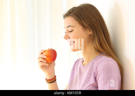 Vista laterale verticale di un felice teen pronto a mangiare un Apple in ambienti interni Foto Stock