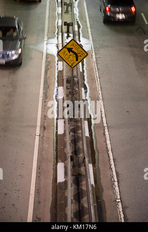 Auto passando da un graffito che legge in portoghese "atteggiamento", spruzzato sulla scheda gialla a sinistra del traffico di segnalazione segno, Sao Paulo, Brasile Foto Stock