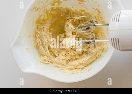 Preparazione di pasta biscotto con le fruste elettriche nel recipiente Foto Stock