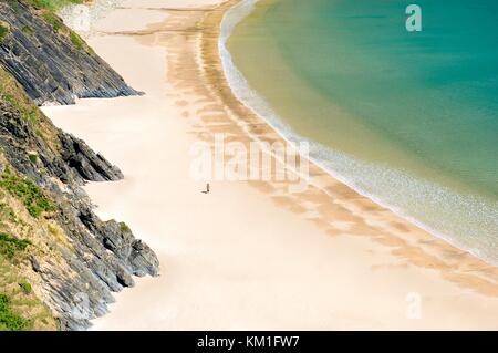 Donna che cammina su argento deserta Strand spiaggia a Malin Beg, Glencolumbkille, County Donegal. Il West End di Slieve League scogliere. Foto Stock