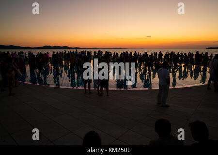 Silhouette di gente sul tramonto colorato nella città di Zadar Foto Stock