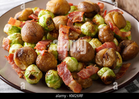 Deliziosa insalata di castagne, cavoli di Bruxelles e la pancetta close-up su una piastra orizzontale. Foto Stock