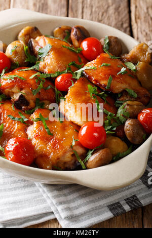 Cosce di pollo arrosto con castagne e i pomodori in una ciotola sul piano verticale. Foto Stock