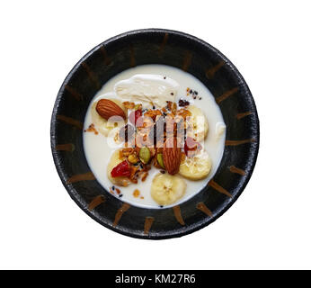 Il Granola cotta e frutti di bosco con latte di soia e banana in una piccola ciotola su sfondo bianco, fragole, mirtilli, vista dall'alto del sano muesli foo Foto Stock