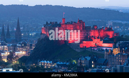 Vista serale del Castello di Edimburgo illuminata in rosso da Salisbury Crags, Edimburgo, Scozia, Regno Unito. Foto Stock