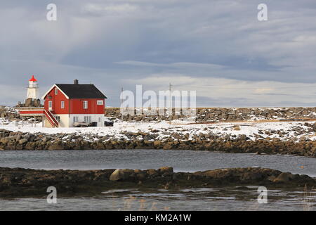 Dipinto di rosso cottage di legno-architettura vernacolare-board e batten schierandosi su bianco pietra dipinta foundation-nero tetto ondulato-piccolo faro Foto Stock