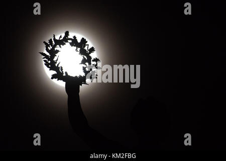 Aberystwyth Galles Regno Unito, domenica 3 dicembre 2017 la "Supermoon", e l'aspetto più ravvicinato e luminoso della luna piena, si arrampica nel cielo dietro la corona tenuta nella mano allungata della scultura dell'Angelo della Pace, in cima al distintivo memoriale di guerra di Aberystwyth. Crediti: keith morris/Alamy Live News Foto Stock