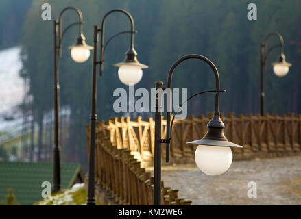 Via la luce di lampade e recinzione di legno sulla strada rurale Foto Stock