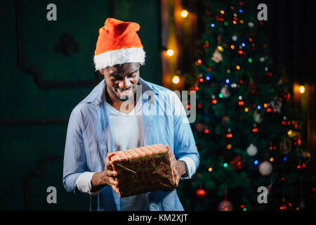 Afro American guy con sorriso affascinante azienda regalo di Natale in mani Foto Stock