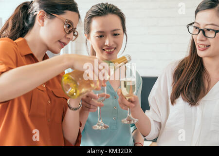 Celebrare il successo aziendale. Close-up di business persone azienda flauti mentre donna manager versando champagne Foto Stock