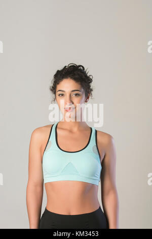 Giovane e bella donna che indossa un reggiseno sportivo sorridente Foto Stock
