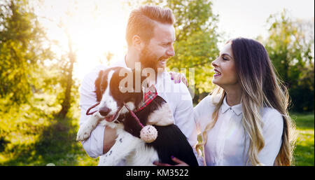 Una giovane coppia a piedi un cane nel parco Foto Stock