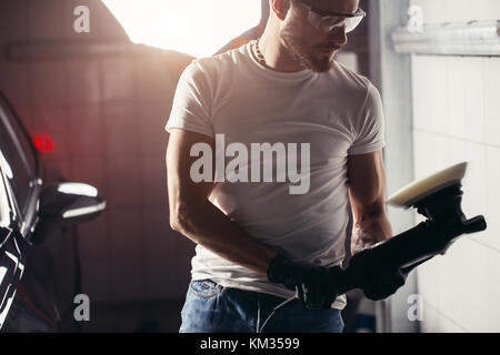 Lavoratore meccanico a preparare per la lucidatura di auto dal buffer di alimentazione macchina Foto Stock