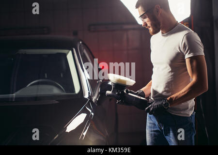 Lavoratore meccanico a preparare per la lucidatura di auto dal buffer di alimentazione macchina Foto Stock