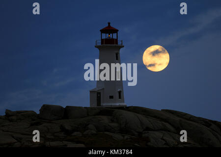 La luna piena sorge dietro la Peggy's Point Lighthouse, Nova Scotia Foto Stock