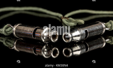 Fischietti realizzati in metallo con una stringa di verde su di loro e una superficie riflettente Foto Stock