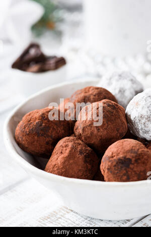 Tartufi di cioccolato in tazza bianco su bianco tavola. Vista ingrandita, il fuoco selettivo Foto Stock