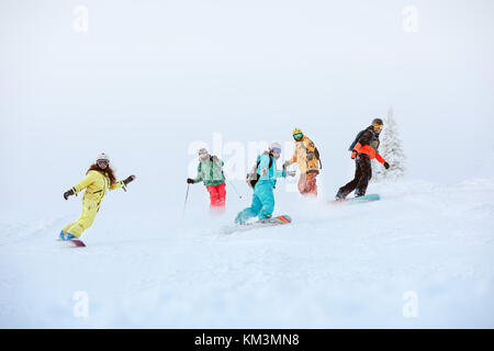 Gruppo di felice snowboarder e sciatori sulle piste da sci Foto Stock