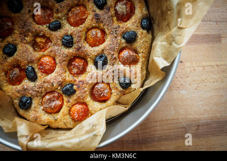 Primo piano di una tipica focaccia pugliese in un vassoio di stagno su una tavola di legno. Lay piatto. Formato orizzontale. Foto Stock