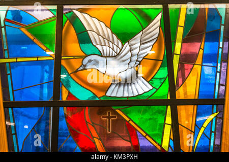 Vetrata in chiesa raffigurante una colomba e croce Foto Stock