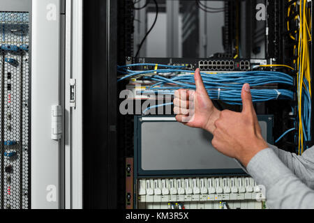 L'uomo fissare la rete di server in data center stanza . Foto Stock