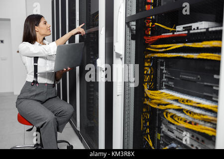 Ritratto del tecnico che sta lavorando sul computer portatile in sala server Foto Stock
