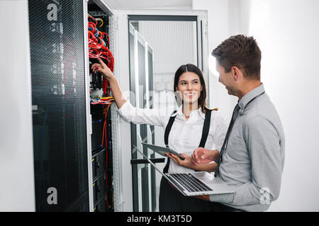 Il team di tecnici che lavorano insieme su server nel centro dati Foto Stock